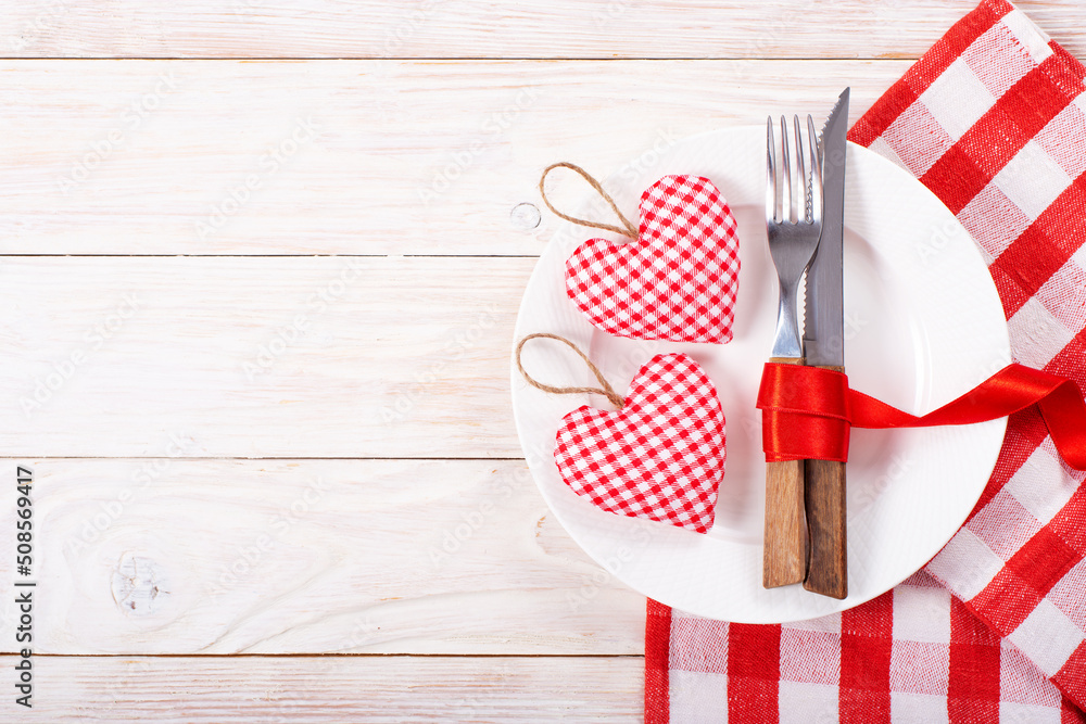 Valentine handmade fabric hearts in plate for romantic dinner flat lay with copy-space background on white wooden table