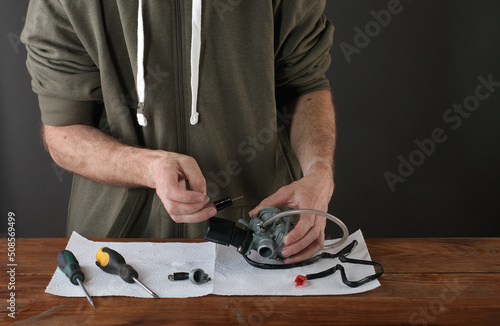 removing the throttle from the carburetor from the scooter on the table by a person