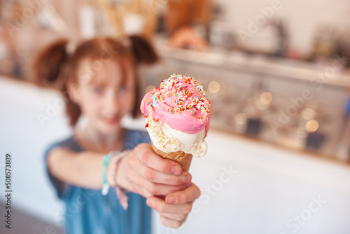 Cute little girl eating ice cream in cafeteria. Child holding icecream. Kid and sweets