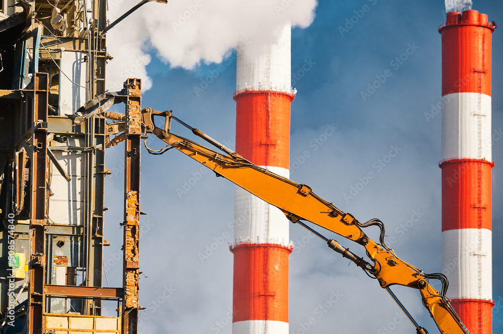 Hydraulic cutter destroys old building against chimneys Hydraulic cutter destroys old building against chimneys