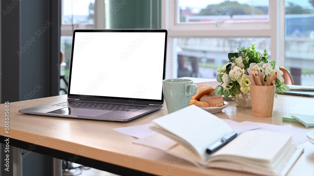 Fototapeta premium Laptop computer, coffee cup and flower pot on wooden table. Blank screen for your advertise text