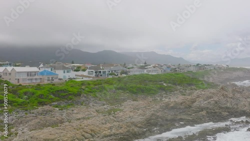 Family houses at sea cost. Waves washing rugged and jagged rocks. Low clouds hiding mountains in background. photo