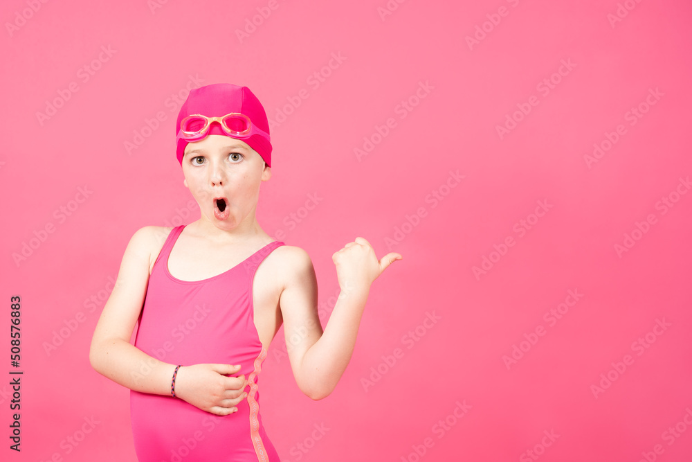 Little surprised swimmer girl pointing at vivid pink copy space. swimming course concept. Little surprised swimmer girl pointing at vivid pink copy space. swimming course concept.