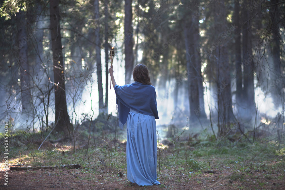 Girl with a torch in the forest. The girl got lost in the forest. Torch.