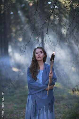 Girl with a torch in the forest. The girl got lost in the forest. Torch.