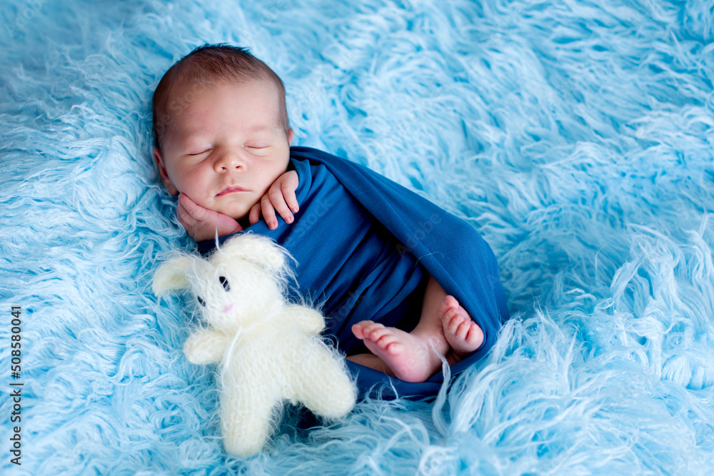 Cute baby boy, peacefully sleeping wrapped in blue wrap Cute baby boy, peacefully sleeping wrapped in blue wrap