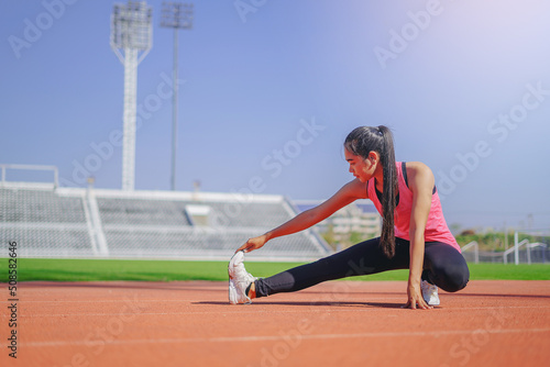 Young woman runner warming up at the racetrack. Fit runner workout, stretch her muscle and warming up at racetrack.
