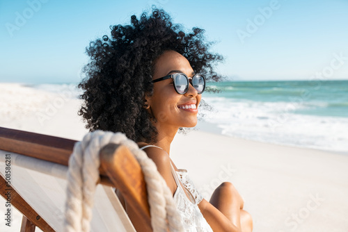 Fotografering Carefree african woman relaxing on deck chair at tropical beach