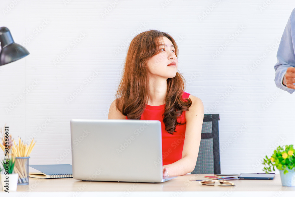 Asian young cheerful lovely handsome husband and beautiful wife couple sitting standing smiling together at desk in living room while female using laptop notebook computer working online from home Asian young cheerful lovely handsome husband and beautiful wife couple sitting standing smiling together at desk in living room while female using laptop notebook computer working online from home