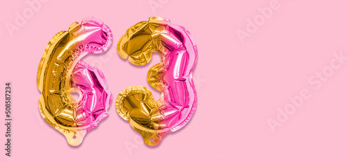 Rainbow foil balloon number, digit sixty three on a pink background. Birthday greeting card with inscription 63. Top view. Numerical digit. Celebration event, template. Banner