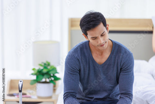 Asian stressed depressed worried upset frowning face young male husband sitting alone on bed packed clothes and stuffs in trolley luggage ready to leave home after terrible fight argument with wife