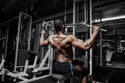 Handsome power athletic bodybuilder training pumping up muscles in gym