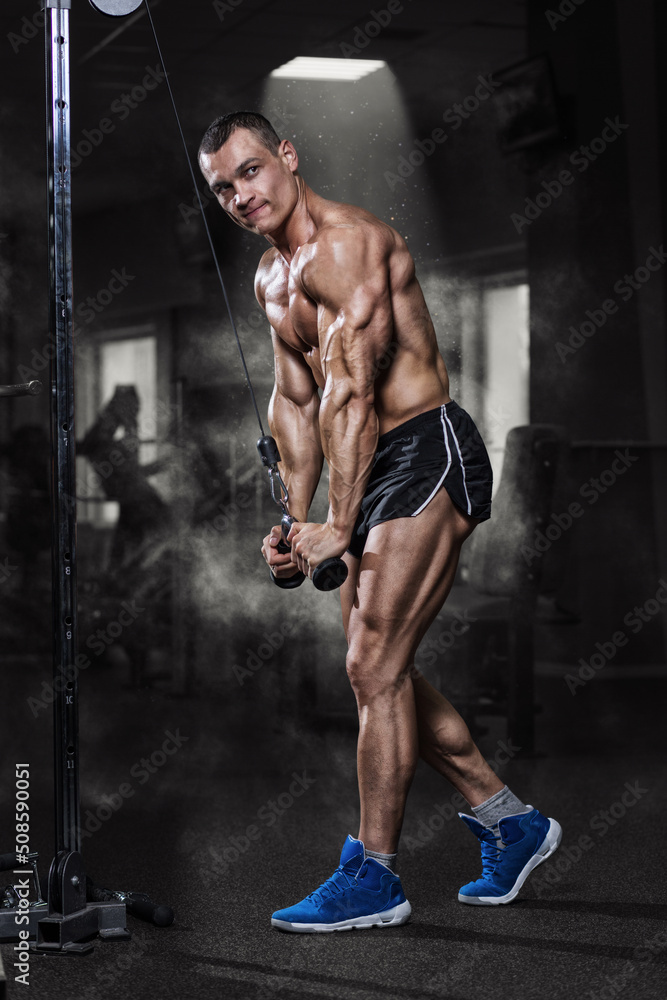 Athlete muscular bodybuilder training on simulator in the gym Athlete muscular bodybuilder training on simulator in the gym