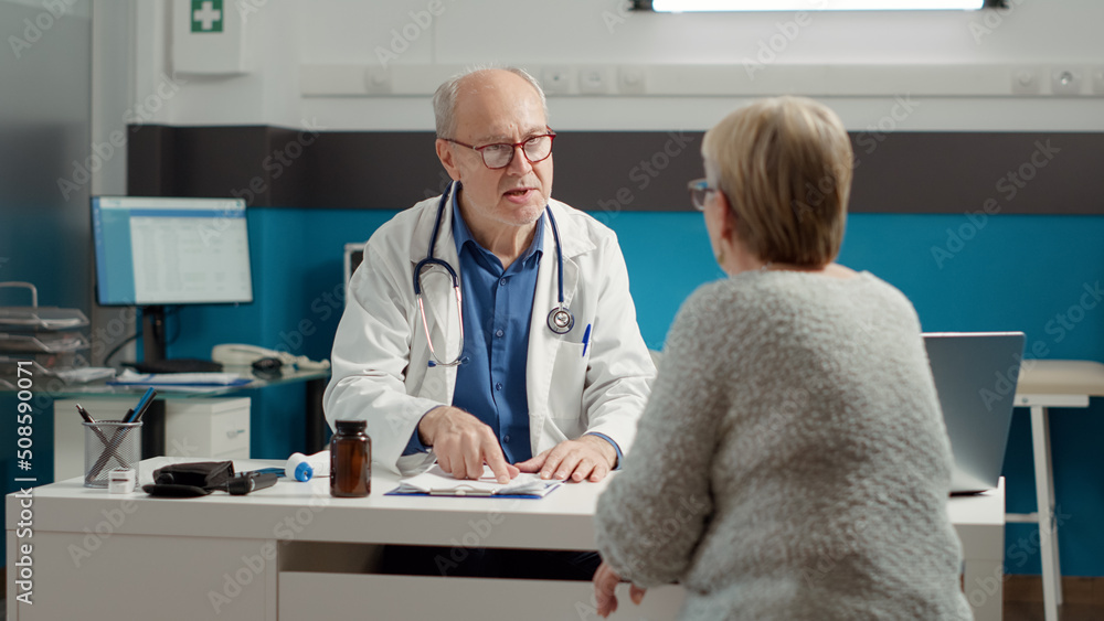 Obraz premium Senior physician doing checkup consultation with retired sick patient in medical office, talking about illness diagnosis. Conversation about disease, recovery and prescription treatment.