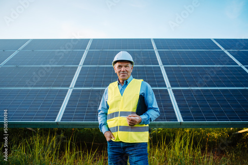 Worker or engineer stands front of solar panels looking at camera. © Big Shot Theory