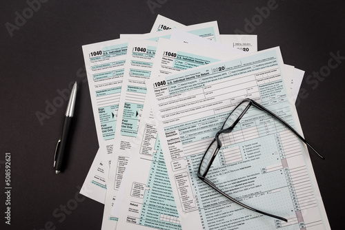top view of tax forms 1040 with pen and glasses