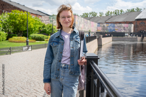 girl in the urban environment. happy student with book in city park.