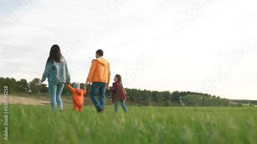 people in the park. happy family a walk at sunset. mom dad and daughter walk holding hands in the park. life happy family kid dream concept. parents and fun baby walking forest park
