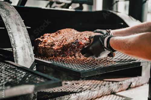 Slika na platnu Chef pitmaster hand cooking grilled beef meat in BBQ smoker.
