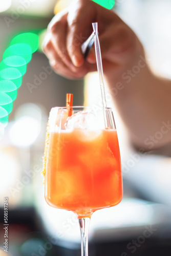 A cocktail glass. Preparation. The bartender's hands put a straw