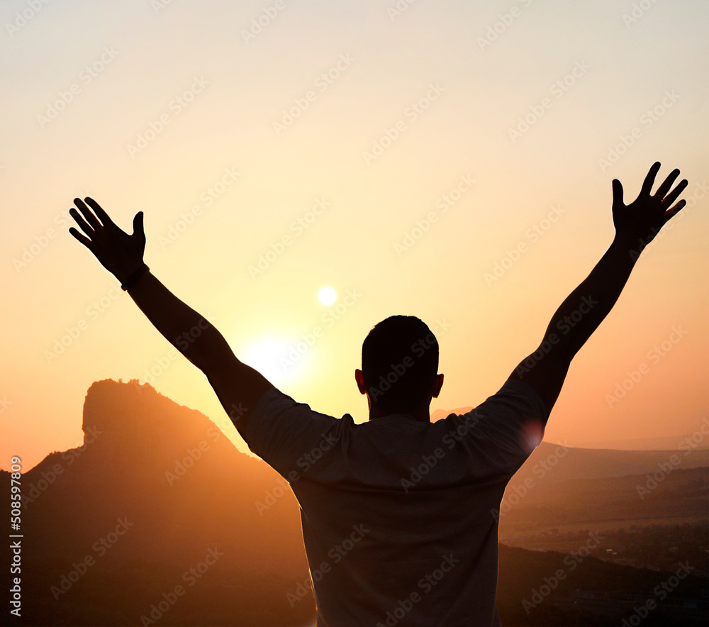 Fototapeta premium silhouette of a man with outstretched arms at sunset outdoors in the mountains