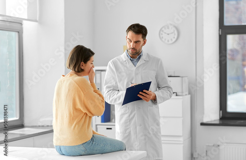 Photography medicine, healthcare and people concept - male doctor with clipboard talking to