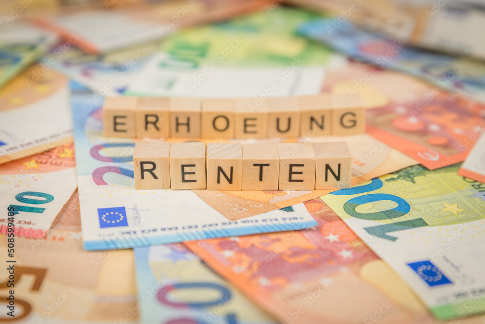 Das Wort Renten – in deutsch für annuity -  und erhoehung – in deutsch für raise -  im Hintergrund auf Geldscheine Euro Euroscheine mit Holzwürfel geschriebener Text