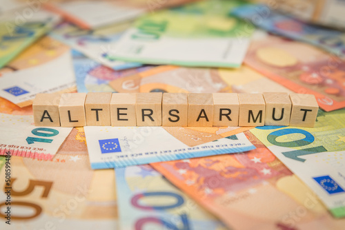 Das Wort Altersarmut – in deutsch für Old age poverty -  auf Geldscheine Euro Euroscheine mit Holzwürfel geschriebener Text