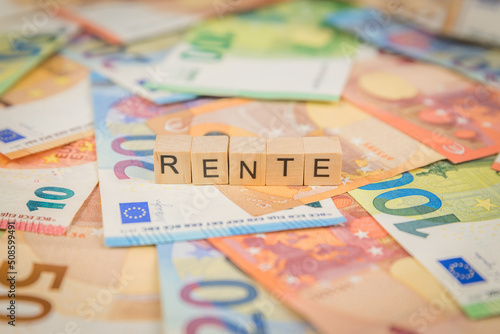 Das Wort Rente – in deutsch für annuity -  auf Geldscheine Euro Euroscheine mit Holzwürfel geschriebener Text