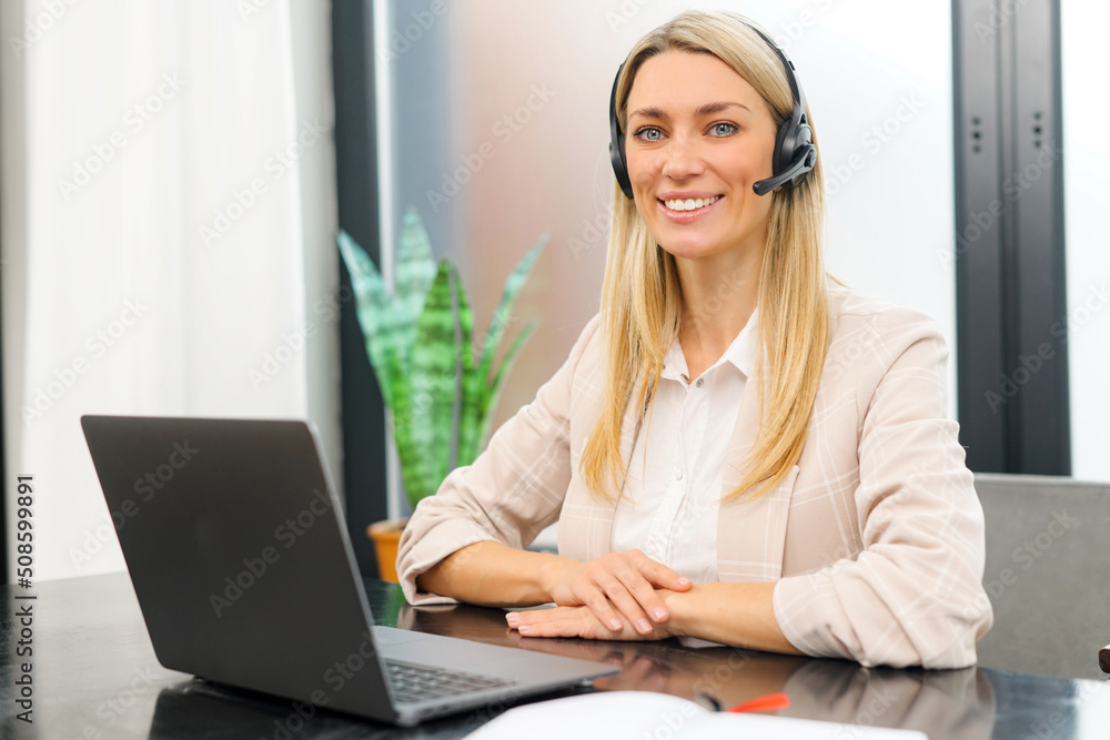 Young female call center operator with hands-free headset talking with client in home office. Concept of remote work. Waist up portrait view Young female call center operator with hands-free headset talking with client in home office. Concept of remote work. Waist up portrait view