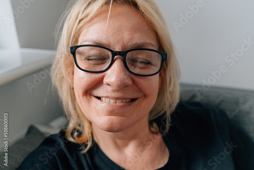 Authentic happy portrait of mature blonde woman with toothy smile ay home
