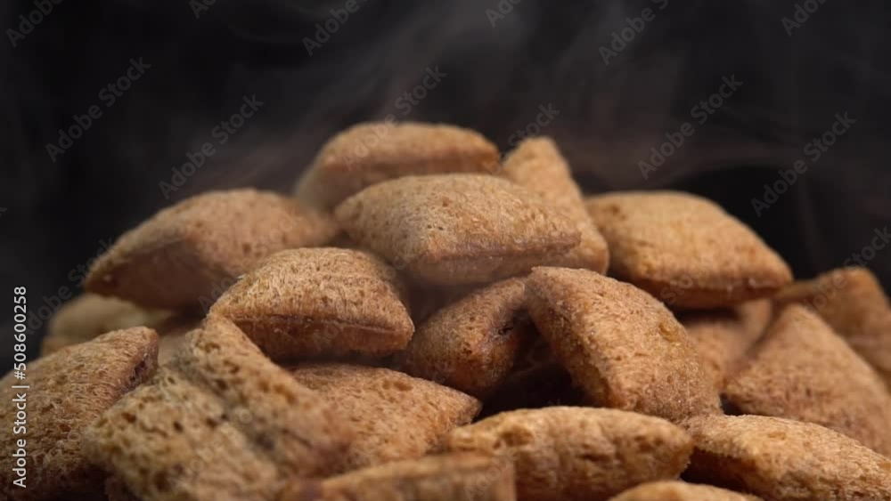Hot crispy chocolate pads with smoke rotate on a black background. Cocoa cereal dessert for a fast breakfast. Morning breakfast dry chocolate pads. Chocolate flakes cereal pads with cream filling. Hot crispy chocolate pads with smoke rotate on a black background. Cocoa cereal dessert for a fast breakfast. Morning breakfast dry chocolate pads. Chocolate flakes cereal pads with cream filling.