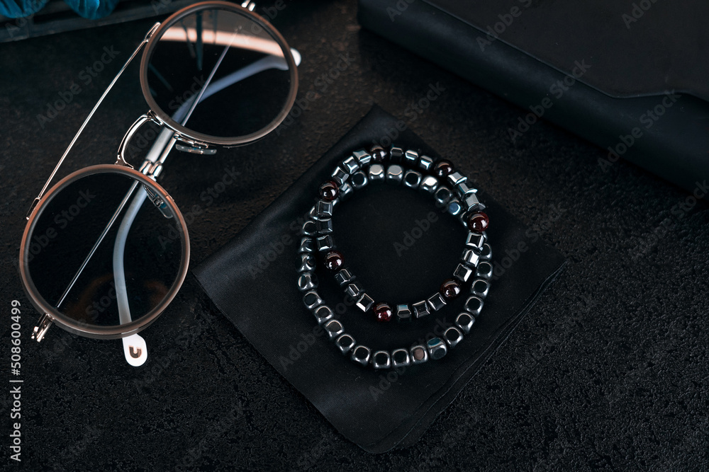 Handmade bracelets made of natural stones on a black cloth. Silver jewelry, sunglasses, close-up
