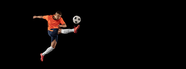 Flyer. Dynamic portrait of professional male football soccer player in motion isolated on dark background. Concept of sport, goals, competition, hobby, achievements