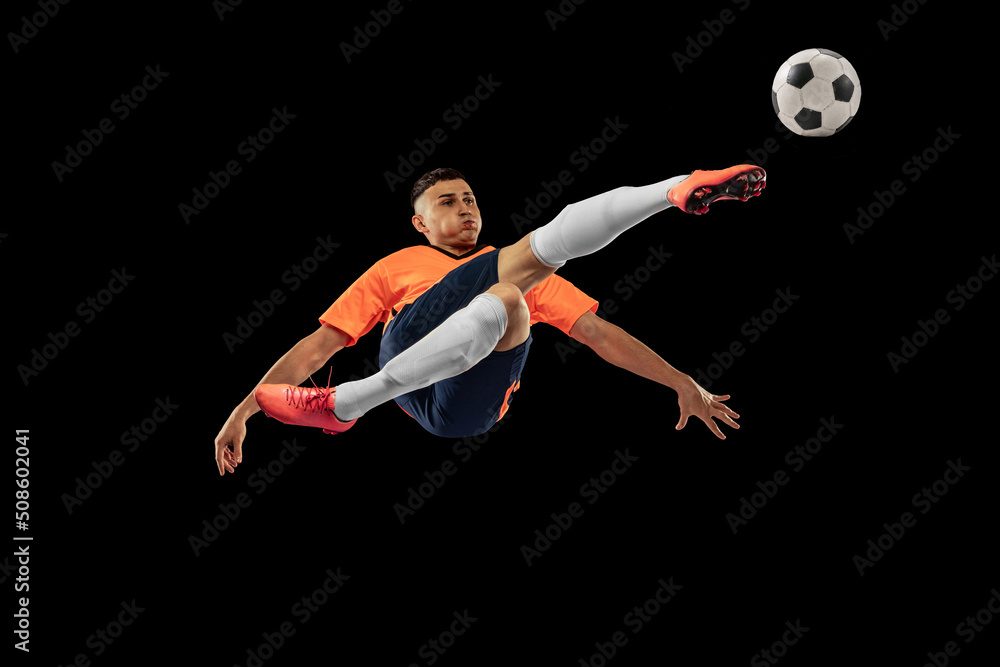 Dynamic portrait of professional male football soccer player in motion isolated on dark background. Concept of sport, goals, competition, hobby, achievements