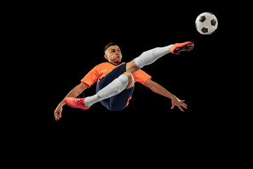 Dynamic portrait of professional male football soccer player in motion isolated on dark background. Concept of sport, goals, competition, hobby, achievements