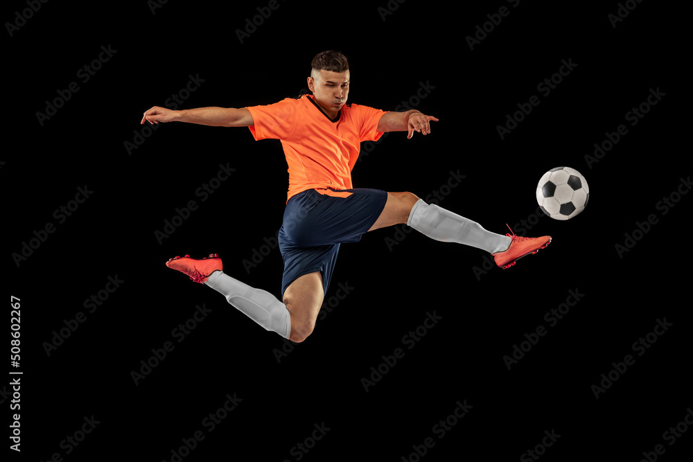 Fototapeta premium Dynamic portrait of professional male football soccer player in motion isolated on dark background. Concept of sport, goals, competition, hobby, achievements