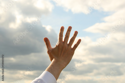 Young man right hand and sky with clouds. Photo was taken 19 May 2022 year, MSK time in Russia.