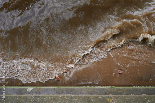 Fototapeta Naklejka Na Ścianę i Meble -  looking down on wave breaking over sand in brown water