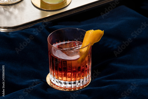 Negroni cocktail, italian recipe with gin, bitter and vermouth; garnished with orange peel, in luxury elegant home, homemade drink photo