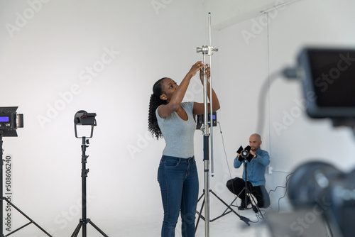 Behind the Scenes in Video Production Studio African American Working Setting Up Film and Lighting Equipment on Movie Set