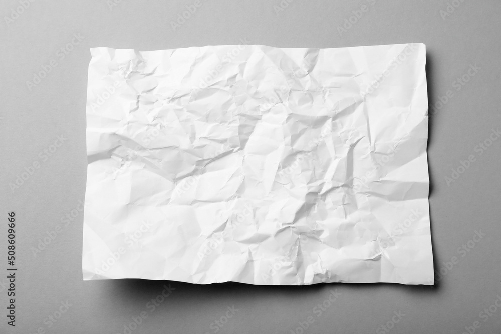 Sheet of white crumpled paper on grey background, top view Sheet of white crumpled paper on grey background, top view