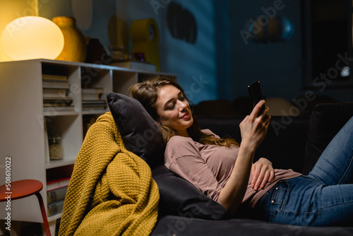Bilde på lerret woman relaxing on sofa and texting messages on smartphone