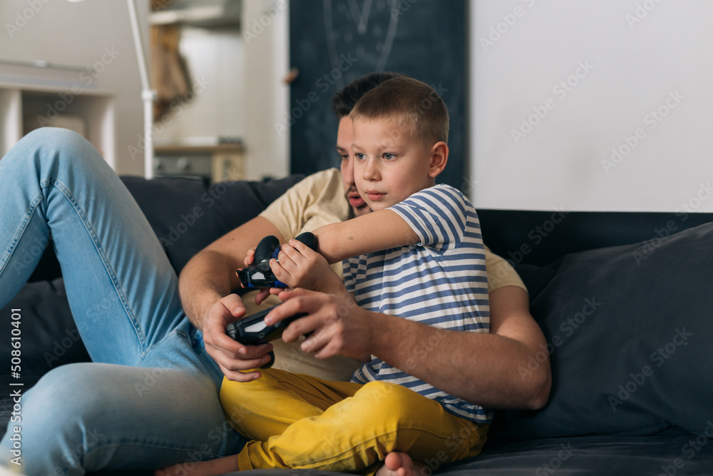 father and son playing video games in living room father and son playing video games in living room