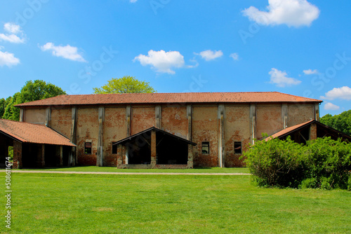 Cascina con alberi prato verde cielo azzurro e nubi