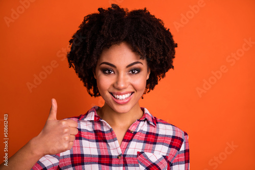 Photo of funky confident lady dressed checkered shirt showing thumb up empty space isolated orange color background © deagreez