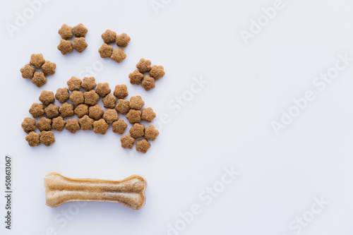 top view of paw shape made of dry pet food near bone isolated on white.