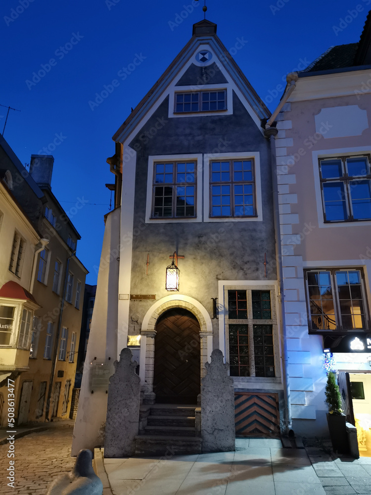 An old low building with an original entrance and a beautiful lantern above it in the city center against the blue sky. Old Tallinn.
