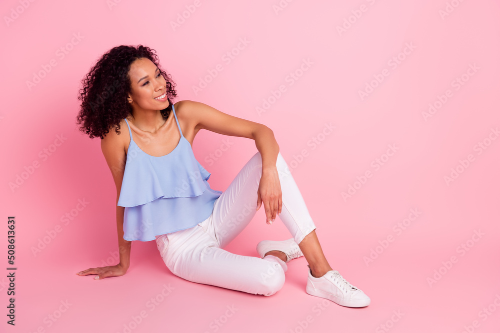 Full body portrait of stunning positive lady sitting floor look interested empty space isolated on pink color background Full body portrait of stunning positive lady sitting floor look interested empty space isolated on pink color background