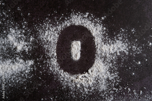 The number 0 is written on scattered white flour through a stencil.